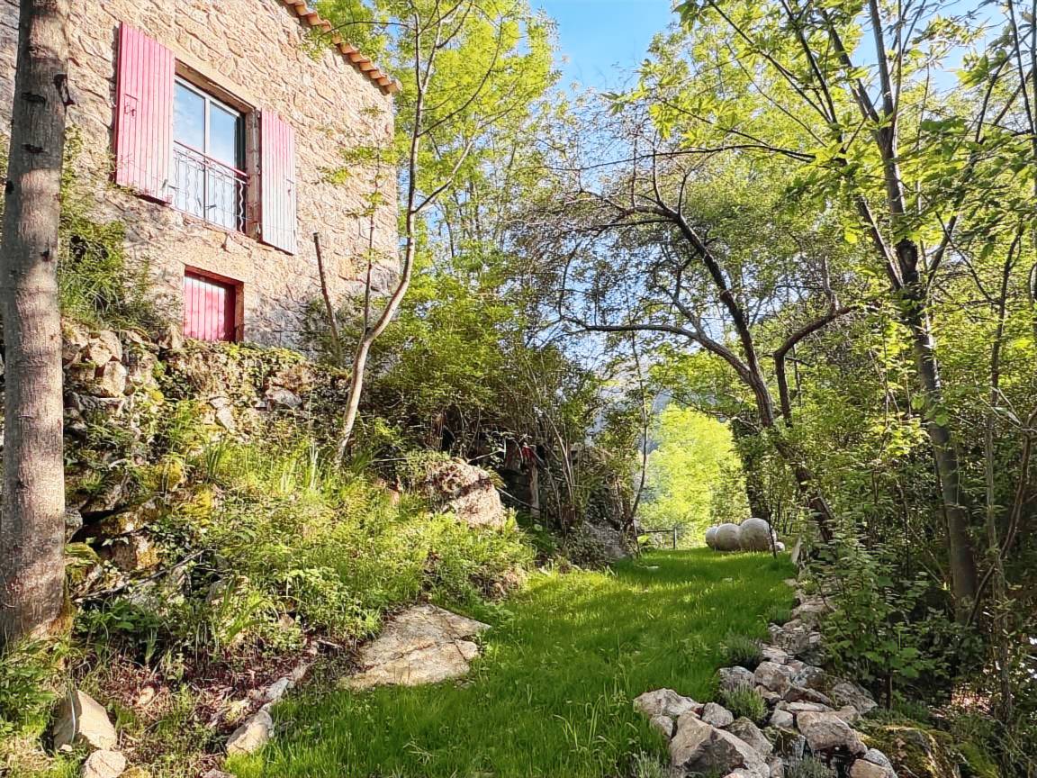 La maison de pierre entourée d'arbres, vue depuis l'extérieur de la propriété