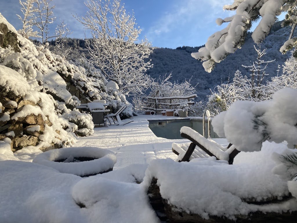 La piscine et sa terrasse recouvertes de neige, les arbres alentour chargés de givre