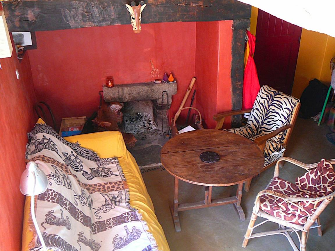 Le salon avec sa cheminée ouverte, un linteau de pierre et des murs rouges