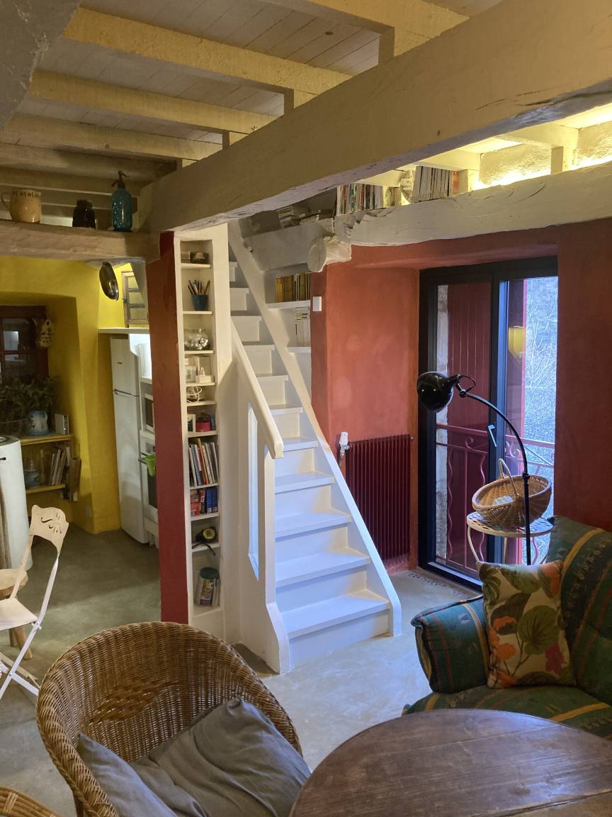 L'intérieur : murs ocre et terracotta, poutres apparentes, escalier blanc